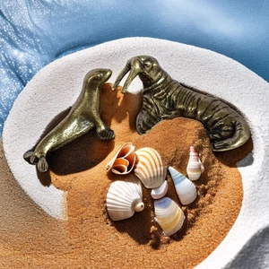 Vista detallada de figuras de morsa y foca en bronce macizo sobre un escenario de arena