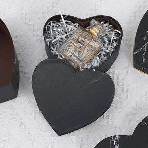 Detail of heart-shaped black matte gift box with silver shredded paper and inner liner