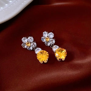 Detailed view of vintage silver flower earrings with yellow crystal drop on red silk