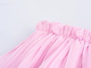 Detail of pink layered ruffle skirt featuring elastic waistband and soft pleated fabric