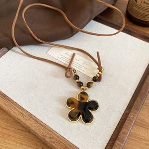 Detailed macro view of vintage leopard resin flower pendant on a brown cord necklace