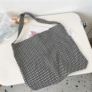 Detailed macro view of the black and white checkered canvas tote bag on a white table