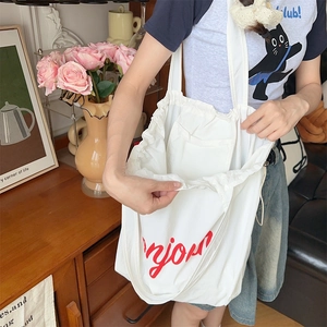 Close-up of white canvas tote bag with red Bonjour print and drawstring closure