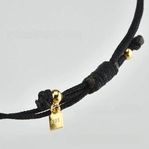 Macro shot of S925 sterling silver tag on a vintage black braided rope chain bracelet