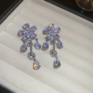 Elegant flower drop earrings with zircon tassels on a white jewelry box background
