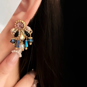 Macro shot of vintage pearl tassel earrings with colorful crystals and gold plating