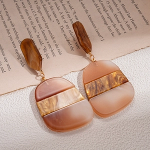 Detailed view of geometric acetate earrings in amber and cream tones on vintage paper