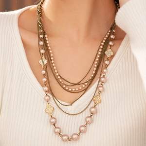 Detailed close-up of multi-layer pearl necklace with sparkling diamond-set flower charms