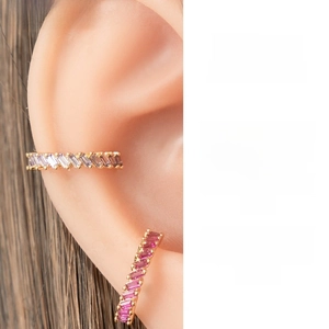 Détail de trois bagues d'oreille colorées serties de zircons sur base dorée