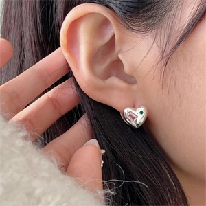 Elegant 925 sterling silver heart earrings with pink and green stones on a model