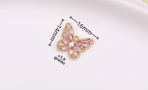 Macro view of a 16x14mm hollow gold butterfly pendant with pink zircon inlays and dimensions