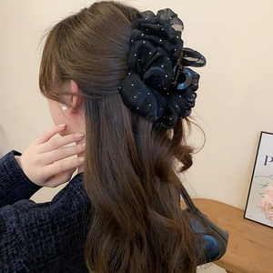 Detail of large black polka dot mesh bow hair claw clip worn on thick wavy hair