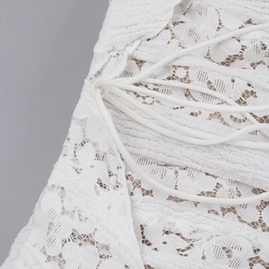 Detail of white floral lace fabric texture and matching drawstring on a dress
