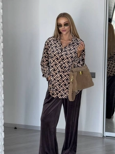 Dettaglio di camicia a maniche lunghe con stampa geometrica e pantaloni in velluto marrone