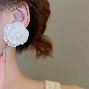 Close-up of a white lace flower earring with a pearl center worn by a female model