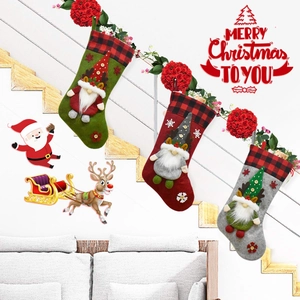 Tre calze di Natale con gnomi e motivi scozzesi appese su una scala decorata a festa
