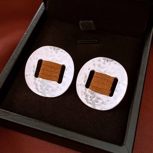 Detail of silver hammered metal earrings with brown leather cord wrap in a black box