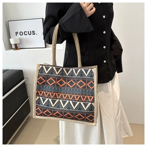 Detailed shot of ethnic geometric pattern tote bag featuring orange and navy jacquard weave