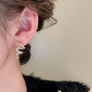Close-up of golden dragon shape earrings with cubic zirconia on a female model