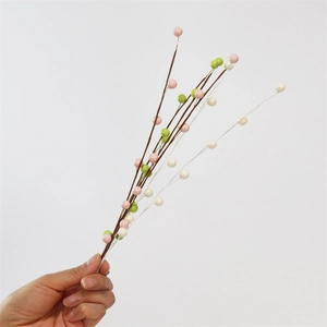 Close-up of hand holding artificial foam berry branches in pink, green and white colors