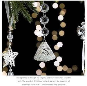 Silver hollow mesh bells and crystal beads hanging on green pine branches