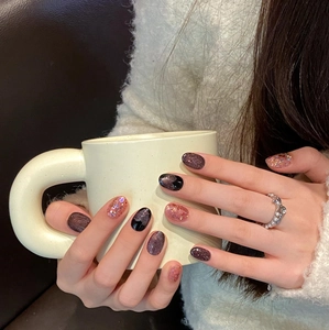 Faux ongles œil de chat rose avec cœurs pailletés et perles dans un décor cosy