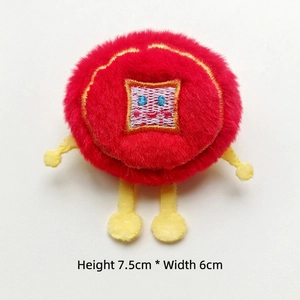 Detail shot of a red plush doll brooch with long fur and yellow limbs, 7.5cm x 6cm size