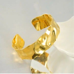 Detail of 18K gold plated wide cuff bracelet with hammered texture and glossy finish
