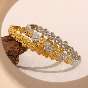 Detaillierte Makroansicht von zweifarbigen Gold- und Silberarmbändern auf dunklem Holz