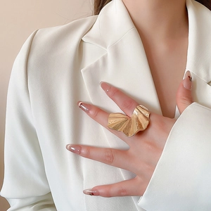 Artistic gold statement ring with ruffled texture worn as a bold chunky fashion accessory