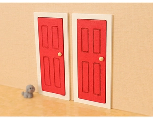 Detailed view of two miniature red dollhouse doors with white frames and round handles