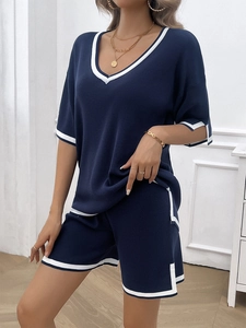 Detail of navy knit lounge set featuring white stripe trim on V-neck top and shorts