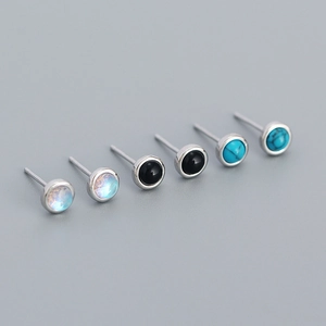 Macro shot of silver stud earrings featuring opal, onyx, and turquoise stones