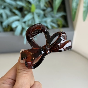 Close-up of deep amber tortoiseshell bow hair claw clip with a glossy finish
