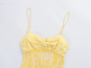 Detail of yellow gingham dress showing smocked waist and delicate front bow design