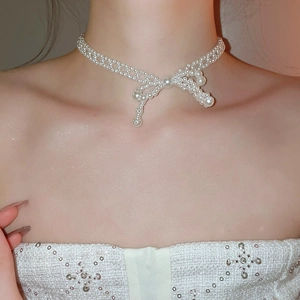 Collier élégant en perles avec nœud porté par un mannequin au design chic en acier inoxydable