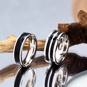 Minimalist titanium steel striped rings with black enamel inlay on natural wood backdrop