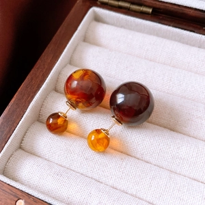 Close-up of vintage resin bead earrings in brown and gold on white velvet lining