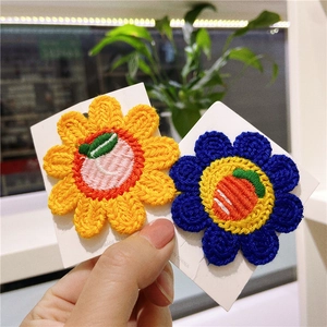 Close-up of knit flower hair clips with peach and carrot embroidery details