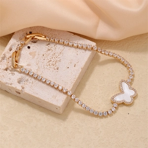 Macro detail of gold butterfly bracelet with white mother-of-pearl and pave zircon stones
