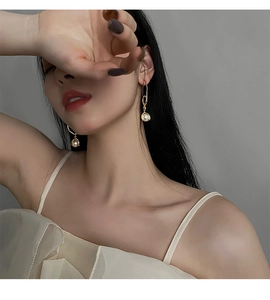 Detailansicht eines eleganten goldenen geometrischen Ohrrings mit glänzender weißer Perle