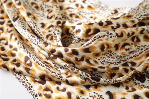 Close-up of leopard print satin scarf fabric showing silk-like texture and soft drapes