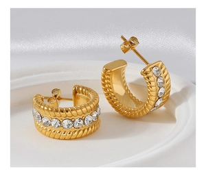 Macro shot of gold-plated C-shaped twisted earrings with sparkling zirconia inlay