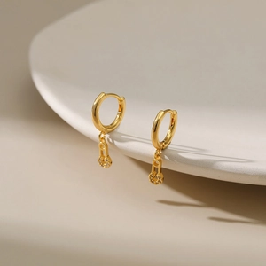 Detailed view of gold plated hoop earrings with zircon encrusted safety pin charms