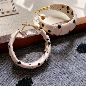 Close-up of retro fabric hoop earrings with black polka dots and gold metal clasp