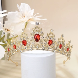 Detailed shot of golden crown featuring red teardrop gems and white rhinestones
