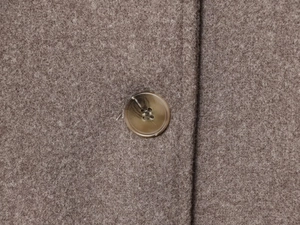 Detailed close-up of brown wool fabric texture and amber-patterned resin button