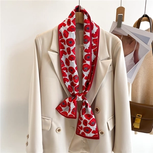 Détail d'un foulard étroit en soie à imprimé floral rouge sur un blazer de bureau beige