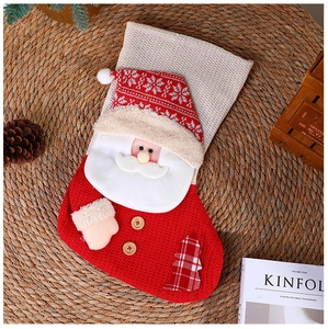 Nahaufnahme einer rot-beigen gestrickten Weihnachtssocke mit einer 3D-Weihnachtsmannfigur