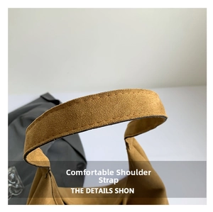 Macro view showing fine stitching on the durable brown suede shoulder strap of the tote bag